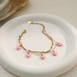 Goldene Edelstahl-Armband mit rosa Herzen und Perlen in der Nahaufnahme.