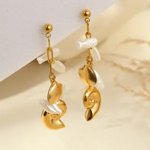 Detailed macro view of gold-plated ocean theme earrings with seashell and fish charms