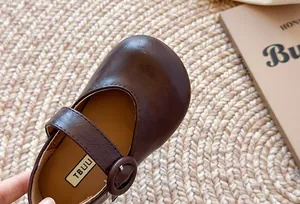 Nahaufnahme von braunen Kinder-Mary-Jane-Lederschuhen mit Textur und Schnalle