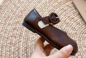 Nahaufnahme der dunkelbraunen französischen flachen Mädchen-Lederschuhe mit Schnalle