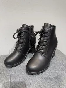 Detailed side view of black lace-up ankle boots with thick high heels and round toe design