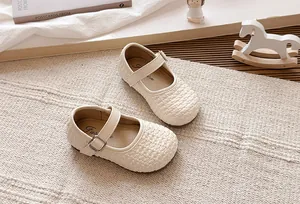 Vista detallada de zapatos Mary Jane tejidos beige para niñas en una alfombra decorativa