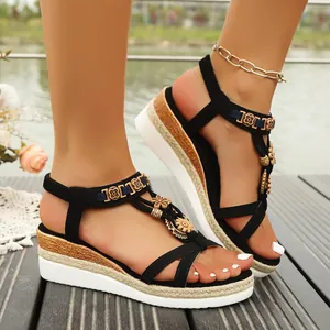 Close-up of bohemian wedge sandals with black straps and floral decorative charms.