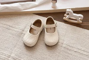 Detalle de zapatos Mary Jane trenzados beige para niñas con textura suave y decoración