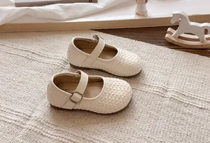 Detalle de merceditas trenzadas color crema para niñas con hebilla ajustable