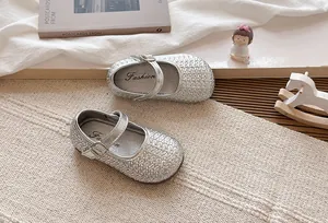 Detalle de zapatos de princesa Mary Jane trenzados plateados para niñas con suelas planas.