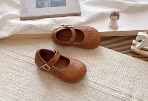Primer plano de zapatos Mary Jane trenzados marrones para niñas con hebilla de metal