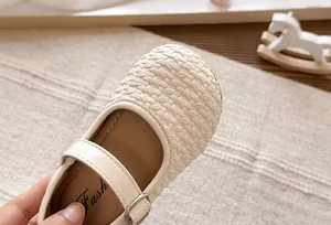 Primer plano de la intrincada textura tejida en las bailarinas Mary Jane crema para niñas.