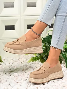 Detail view of beige suede platform espadrille loafers with stylish tassel accents.