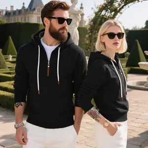 Pareja con sudaderas negras de forro polar grueso en un elegante jardín exterior