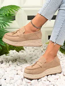 Detailed side view of beige suede platform espadrille loafers featuring decorative tassels
