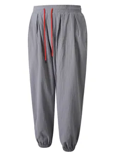 Vista detallada de pantalones de lino grises con cordón rojo y cintura elástica.