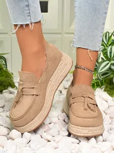 Detailed macro view of beige suede platform loafers featuring jute espadrille soles and tassels