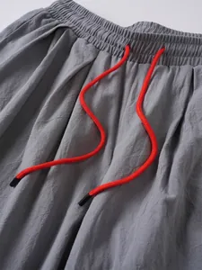 Primer plano de pantalón de lino gris para hombre con cordón naranja y cintura elástica