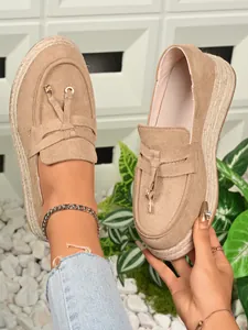 Detailed view of women's beige platform loafers featuring tassels and braided espadrille soles.