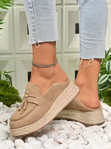 Close-up of khaki suede platform espadrille mules with fringe and woven jute sole.