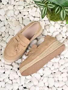 High-angle detail view of khaki suede platform espadrille loafers on white pebbles background.