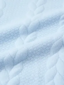 Macro detail of light blue knitted sweater showing elegant textured leaf jacquard pattern
