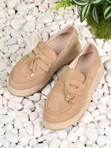 Detail shot of khaki suede espadrille loafers with platform soles and decorative tassels.