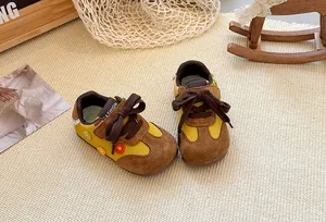Detailed view of kids' yellow and brown German trainer shoes with flower accents