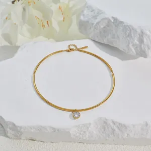 Detail view of a gold-plated stainless steel choker with a single round crystal pendant