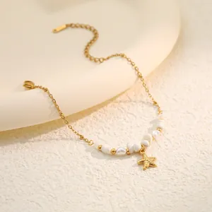 Detailed view of a gold stainless steel bracelet with starfish pendant and white shell pearls