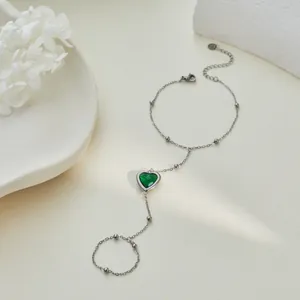 Dettaglio di un bracciale da dito in argento con cuore verde smeraldo sfaccettato.