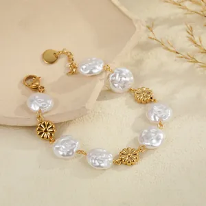 Macro view of a gold stainless steel bracelet featuring Baroque pearls and daisy charms