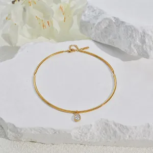Close-up of a gold-plated stainless steel choker with a pear-cut crystal pendant on stone