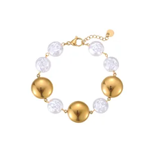 Detail view of a gold stainless steel bracelet with white baroque pearls and discs.