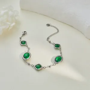 Vista dettagliata di un elegante bracciale argento con pietre ovali verde smeraldo sfaccettate.