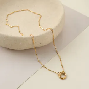 Primo piano di una collana in acciaio inossidabile dorato con catena a barre e chiusura ad anello