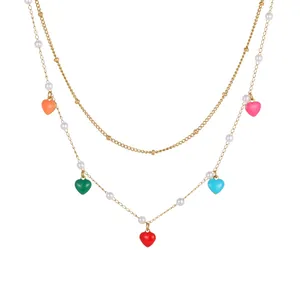 Nahaufnahme von bunten Emaille-Herzanhängern und Perlen an goldener Edelstahlkette