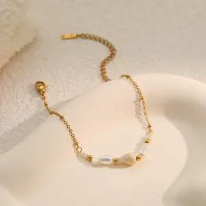 Detail shot of a gold stainless steel bracelet featuring natural pearls and shell
