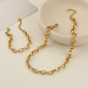 Detail view of an embossed stainless steel link necklace and bracelet set in gold finish.
