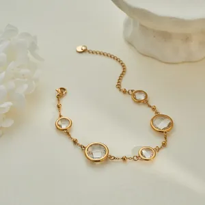 Close-up of gold chain bracelet featuring faceted clear crystals in an elegant setting.