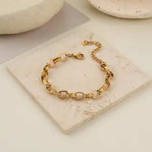 Detail view of a luxury gold stainless steel embossed chain bracelet on a stone block