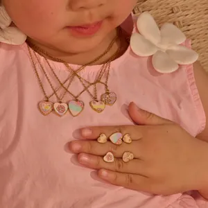 Detailopname van kleurrijke hartvormige glitter emaille sieradenset gedragen door een kind