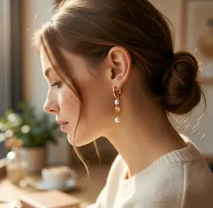 Vista de perfil de una modelo con aros dorados con perlas blancas y una estrella