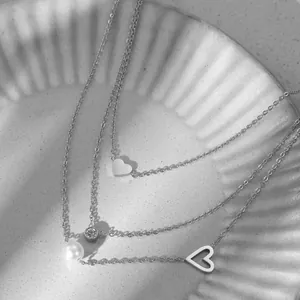 Détail d'un collier à trois rangs en acier inoxydable avec cœurs et perle élégante