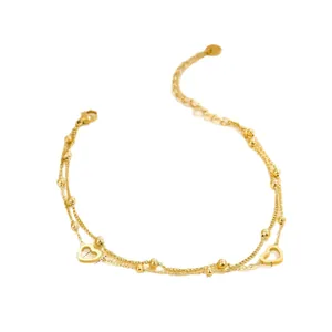 Detalle de la tobillera multicapa de acero inoxidable dorado con corazones de mujer
