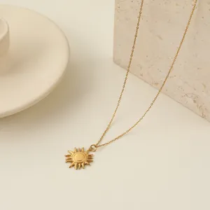Dettaglio macro di una collana con ciondolo a sole in acciaio dorato su un blocco di pietra