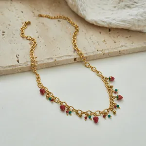 Detail einer goldenen Edelstahlkette mit roten Erdbeeranhängern und bunten Perlen.