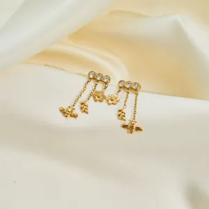 Macro view of elegant gold stainless steel earrings featuring bee and flower tassels.