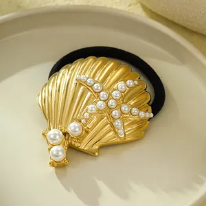 Macro view of a golden stainless steel shell hair tie with a pearl-inlaid starfish motif.