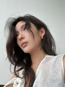 Mannequin portant des boucles d'oreilles en émail orange en forme de goutte