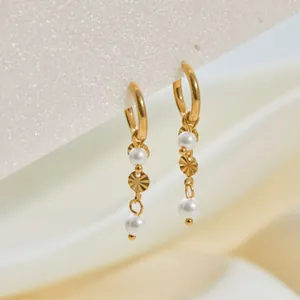 Detalle de los elegantes pendientes de acero chapados en oro con perlas blancas