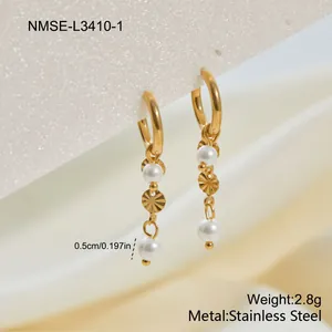 Detalle de pendientes de aro de acero inoxidable dorado con elegantes perlas y discos.