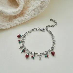 Detailansicht eines silbernen Armbands aus Edelstahl mit roten Erdbeeranhängern