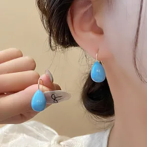 Gros plan de boucles d'oreilles goutte en acier titane bleu portées par un mannequin